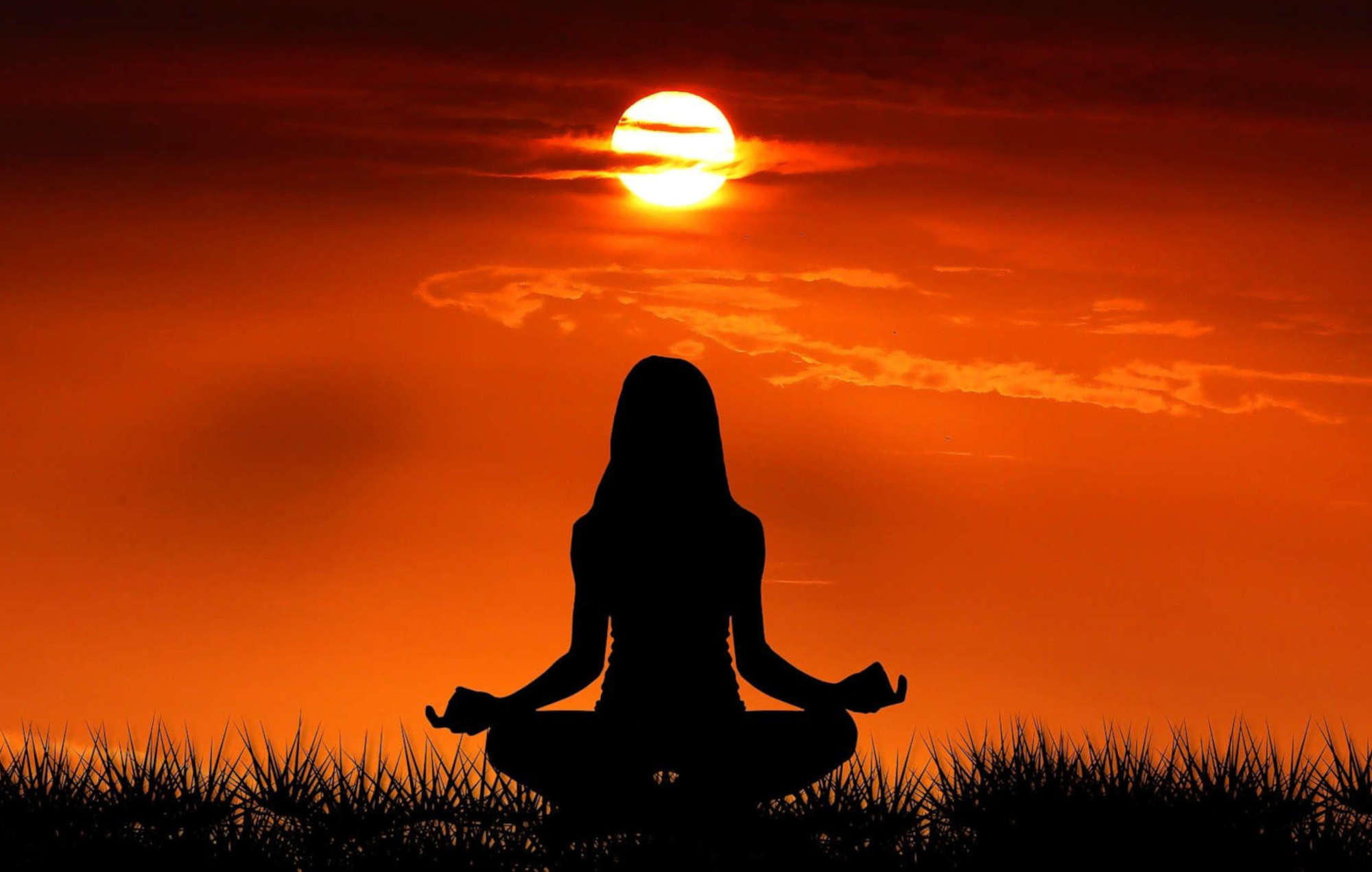 Silhouette Frau Meditation vor Sonnenuntergang und Himmel orange