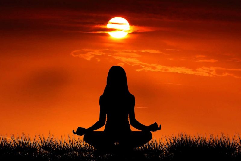 Silhouette Frau Meditation vor Sonnenuntergang und Himmel orange